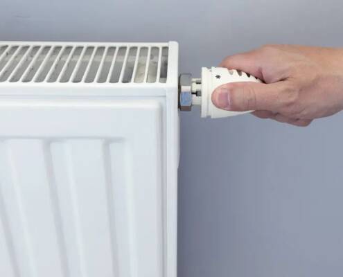 Drehen des Heizkörperventils an einem weißen Flachheizkörper