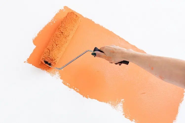 Anstreichen einer Wand mit orangener Wandfarbe