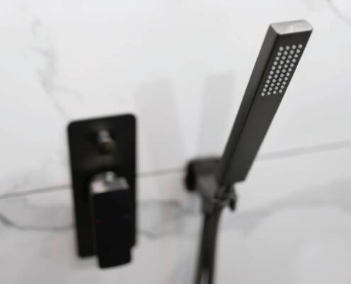 Minimalistische schwarze Duscharmatur mit eckiger Handbrause vor einer Wand mit Marmoroptik