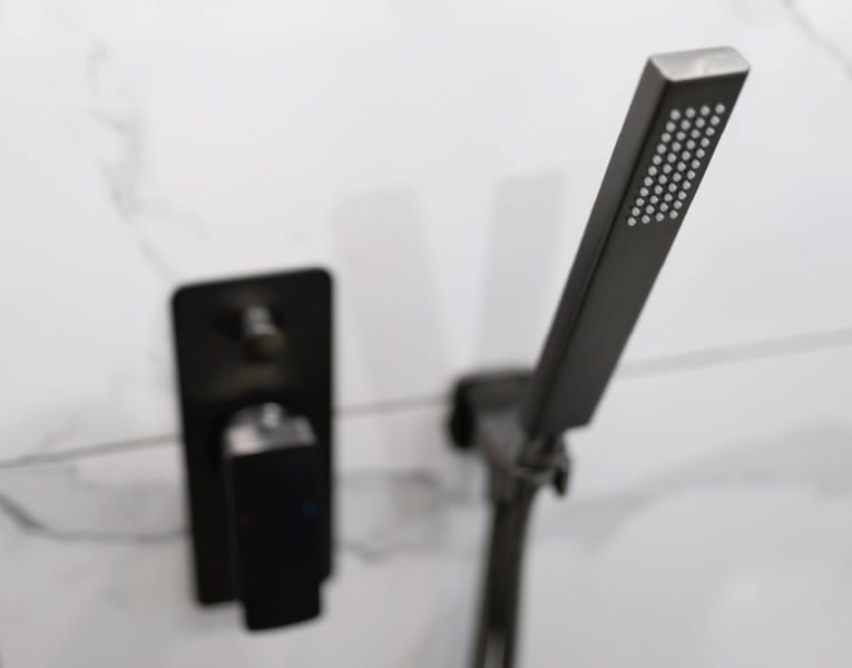 Moderne schwarze Duscharmatur mit Handbrause in eckigem Design Minimalistische schwarze Duscharmatur mit eckiger Handbrause vor einer Wand mit Marmoroptik